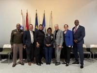 Six resource fair speakers and the National Anthem singer pose together on the stage following the speaking program.